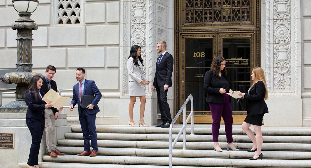 Seven students converse on the steps of a government building